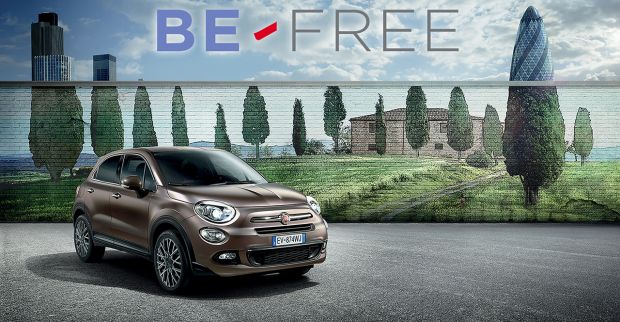 automobile 500 x fiat in un paesaggio con una collina nello sfondo e pini riportante la scrittura be free